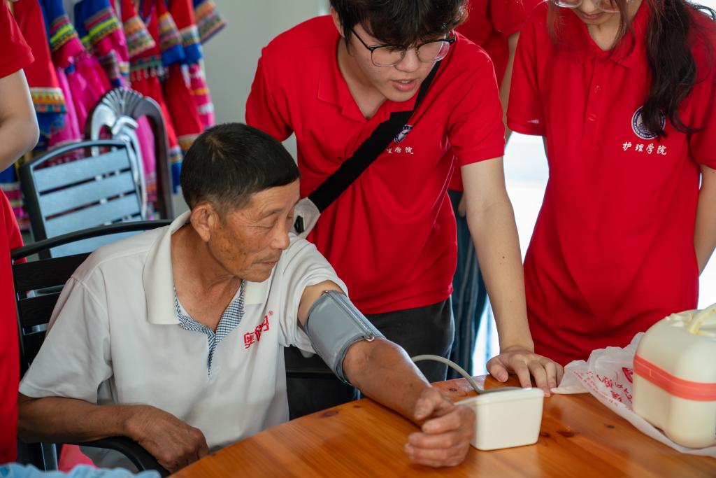 图为实践队成员为上金贝老人进行血压测量及健康宣传.jpg